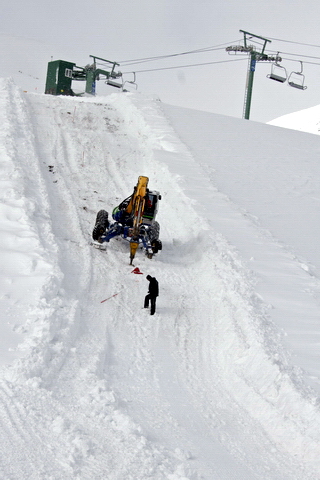 Installing poles and anchors for impact netting on the FIS race track.